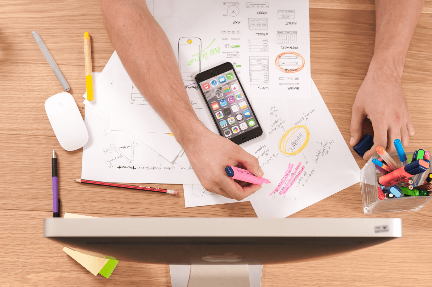 Hands marking up website sketches on a desk